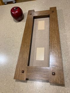 an apple sitting on top of a counter next to a wooden frame