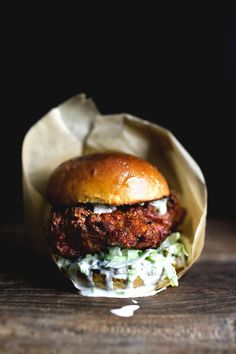 a fried chicken sandwich with coleslaw and mayonnaise on a wooden table