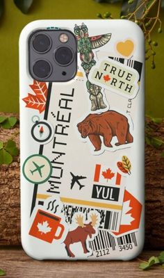 an iphone case with stickers on it sitting next to some leaves and branches in the background