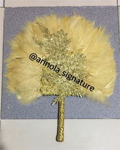 a gold and white feather fan on top of a table