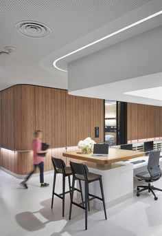 an office with two desks and chairs in front of a counter top that has flowers on it