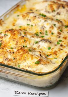 a casserole dish with cheese and meat in it on a table next to a piece of paper