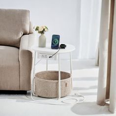 a white table with a cell phone on it next to a beige couch and window