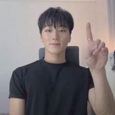 a young man is making the peace sign with his hand while sitting in an office chair