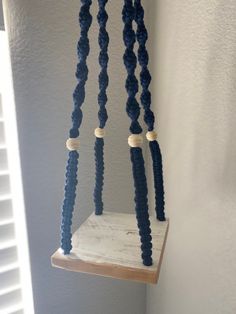 a bird feeder with beads hanging from it's sides in a corner next to a window