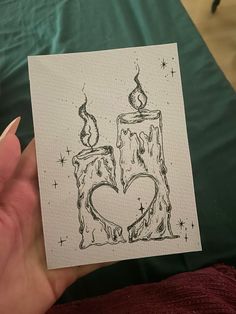 a person holding up a card with a drawing of a candle in the shape of a heart