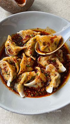 a white plate topped with dumplings covered in sauce