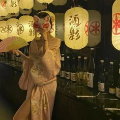 a woman in a kimono holding up a fan next to some bottles and lights