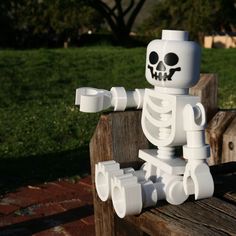 a lego skeleton sitting on top of a wooden bench