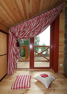 the interior of a cabin with wood floors and striped curtains on the windowsills