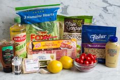 the ingredients for this meal are laid out on a marble counter top, including lemons, tomatoes, onions, and other foodstuffs