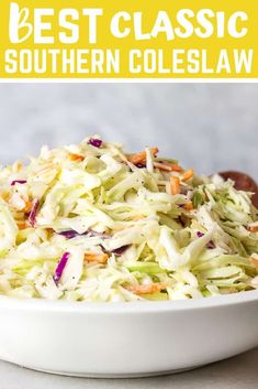 a white bowl filled with coleslaw on top of a table next to a wooden spoon