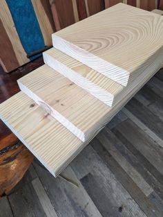 three pieces of wood sitting on top of a wooden floor next to a blue chair