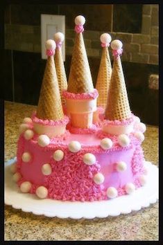 a cake with pink frosting and cones on top is sitting on a countertop