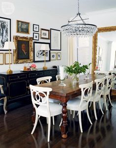 a dining room table with white chairs and a chandelier hanging from the ceiling