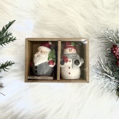 two ceramic snowmen in a box with christmas decorations