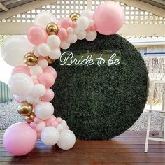 a bride to be balloon arch with pink, white and gold balloons in front of it