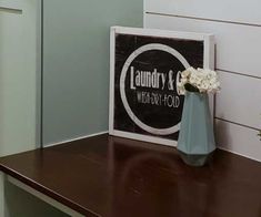 a vase with white flowers sitting on top of a wooden table next to a sign