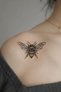 a woman's chest with a tattoo of a bee on her left side shoulder