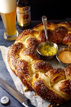 a large pretzel bread with dipping sauces on the side