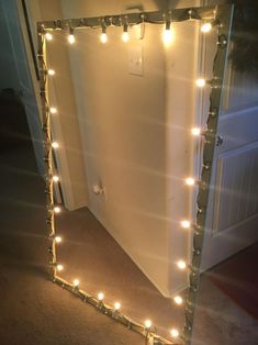 a mirror that has lights on it in front of a door with a light up frame