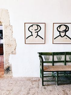 two paintings hang on the wall next to a bench in a room with peeling paint