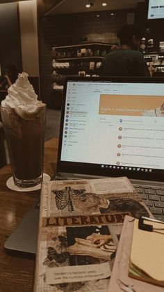 an open laptop computer sitting on top of a wooden table next to a cup of coffee