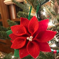 a red poinsettia ornament hanging from a christmas tree