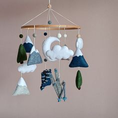 a mobile made out of felt hanging from a wooden beam with clouds and mountains on it