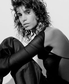 a black and white photo of a woman with curly hair wearing a sheered dress