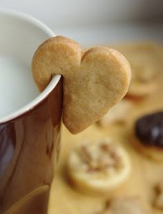 a heart shaped cookie is sticking out of a coffee cup with cookies in the background