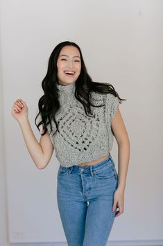 a woman is smiling and posing for the camera with her arms in the air while wearing high rise jeans