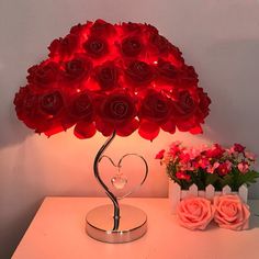 a lamp that is on top of a table with flowers in the vase behind it