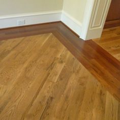 an empty room with hard wood flooring and white trim on the walls, along with a wooden door