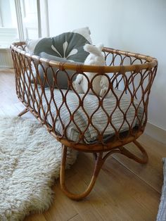 a baby in a crib on the floor next to a white rug and window