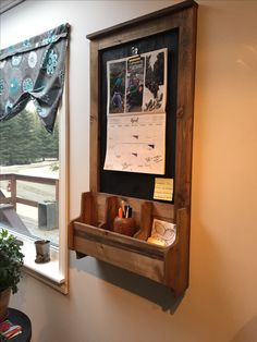 a bulletin board mounted to the side of a wall next to a potted plant