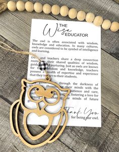 an owl wooden necklace with a note attached to it on top of a wood table