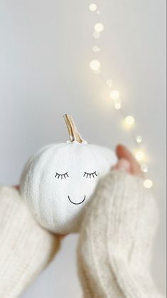 a person holding a white pumpkin in their hands