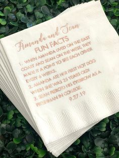 four white napkins with writing on them sitting in some green plants and leaves around them