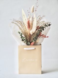 a flower arrangement in a paper bag on a white background