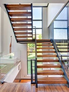 the stairs in this modern house are made out of wood and steel, with glass railings