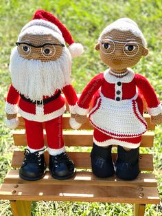 two crocheted santa and mrs claus dolls sitting on a bench