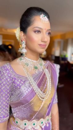 a woman in a purple and gold sari with pearls on her head, wearing jewelry