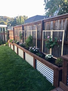 a fenced in garden area with flowers and plants growing on the side of it