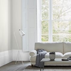 a living room with a white couch, table and lamp in front of a large window