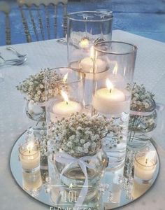 a table with candles and flowers on it next to a swimming pool in the background