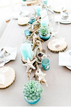 the table is set with blue and white dishes, silverware, and succulents