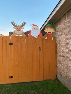 a wooden fence with paper cutouts of santa, reindeer and snowman on it