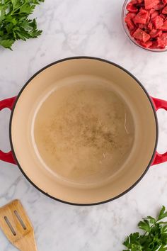 a pot filled with liquid next to some chopped up tomatoes and parsley on the counter