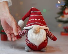 a hand reaching for a knitted santa clause doll